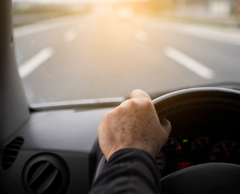 truck driver's hands on wheel looking out into road